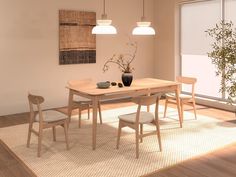 a dining room table with four chairs and a potted plant in the corner on the rug