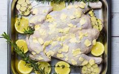 raw chicken with lemons and rosemary on a baking sheet, ready to be cooked