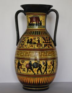 a large vase with designs on it sitting on a table next to a white wall