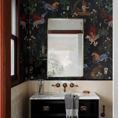 a bathroom sink with a mirror above it and wallpaper on the walls behind it