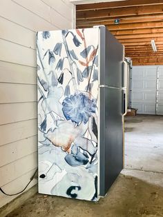 the refrigerator is painted with flowers on it's front and side doors, in an unfinished garage