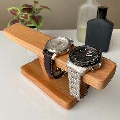 two watches are sitting on a wooden stand