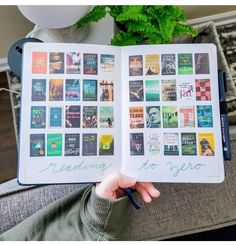 someone is holding an open book with many books on it in front of a potted plant