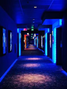 an empty hallway lit up with blue lights and posters on the walls, along with carpeted flooring