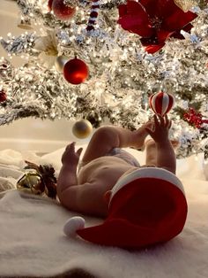 a baby laying in front of a christmas tree