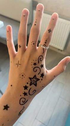 a person's hand with black ink on it and stars in the sky above them