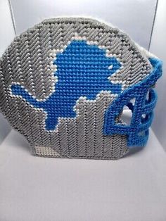 a blue and gray beaded basket with an elephant on the front, sitting on a white surface