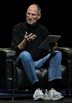 an older man sitting in a chair holding a tablet