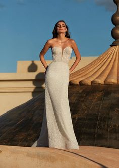 a woman in a wedding dress posing for the camera with her hands on her hips