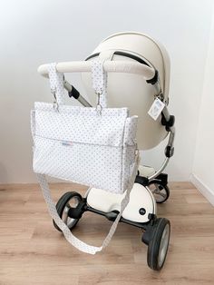 a baby stroller with a white bag on it's back, sitting in front of a wall