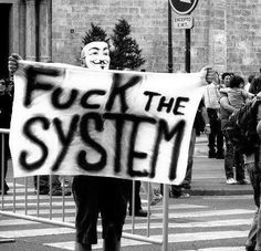 a protester holding a sign that reads f k the system