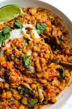 a white bowl filled with mexican food and garnished with sour cream, cilantro, green leafy