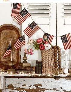 an american flag garland is hanging on the wall above a mantle with flowers and candles