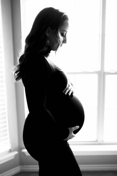 a pregnant woman standing in front of a window