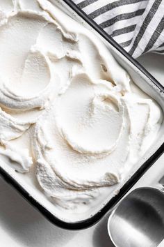 a pan filled with whipped cream next to two spoons