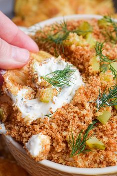 a person dipping some kind of food into a bowl with sour cream and dill