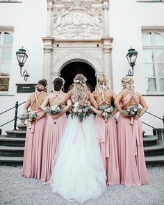 a group of bridesmaids standing in front of a building with their backs to the camera