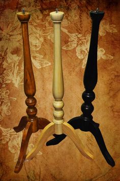 three wooden candlesticks sitting next to each other on a brown and black background