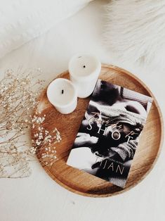 two candles and a book on a wooden tray