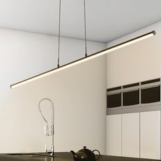 a kitchen with a kettle on the counter and lights hanging from the ceiling above it