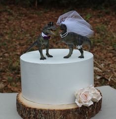 a dinosaur wedding cake topper with a bride and groom