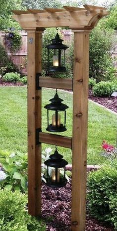 a wooden structure with lanterns hanging from it's sides in the middle of a garden