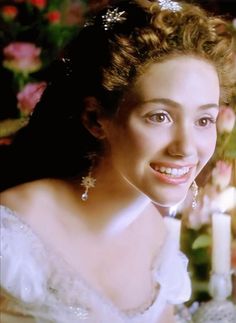 a woman wearing a tiara and smiling for the camera with candles in the background