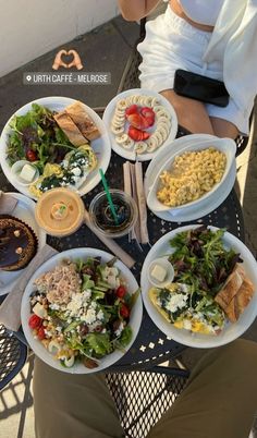 a woman sitting at a table filled with plates of food