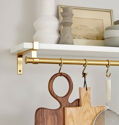 the kitchen utensils are hanging on the shelf above the cutting board and rack