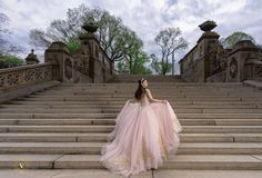 a woman in a pink dress sitting on some steps