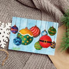 a card with ornaments on it next to a christmas tree