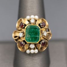 Renaissance Revival Emerald Garnet Diamond and Pearl Statement RIng in 14k Yellow Gold This knockout of a ring bring back visions of Renaissance jewelry- rich in colors and intricate in design.  The ring features a center emerald cut emerald which is bezel set.  The emerald has a closed back so we can't calculate the weight precisely, however it measures 10mm x 8.5mm, roughly calculating to 3.00ct.  The stone is framed by four diamonds that measures 2.5mm each, totaling 0.24cttw.  2.8mm garnets Heirloom Multi-stone Yellow Gold Gemstones, Yellow Gold Multi-stone Jewelry For Anniversary, Anniversary Multi-stone Yellow Gold Jewelry, Multi-stone Emerald Gold Jewelry, Luxury Multi-stone Emerald Jewelry, 14k Gold Emerald Ring With 17 Jewels - Collectible, Elegant Gold Emerald Ring With Gemstone Accents, Heirloom Multi-stone Yellow Gold Jewelry, Antique Multi-stone Formal Jewelry