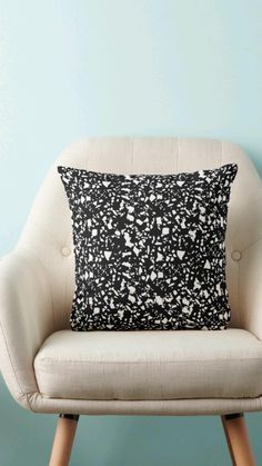 a black and white pillow sitting on top of a wooden chair next to a blue wall