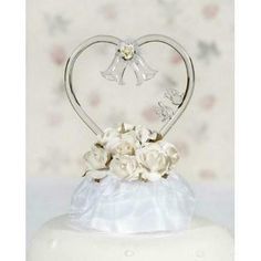 a wedding cake with a heart shaped topper and white flowers on it's side