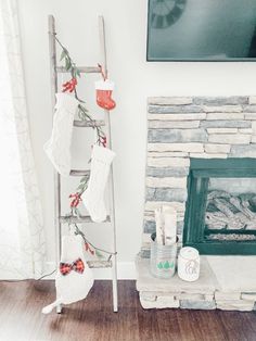 stockings hanging from a ladder in front of a fire place with candles and other items