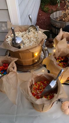 several bowls filled with candy corn on top of a white table cloth covered tablecloth