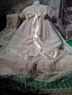 "HERITAGE, offers traditional, classic lines with vintage appeal using a embroidered english net. Tailored for the Little Gent or Little Miss. Features a rounded neckline, Cap sleeves designed to carry the theme of the gown. Gown is long flowing to a approximate length of 36\". Hemline showcases the beautiful inlays of lace. Sash is added to complete the look of this retro vintage look hoping to capture the allure of yesteryears. Color is a light ivory, with a very soft touch. Slip included. Cus Traditional Fitted Cream Gown, Traditional Cream Dress For Ceremony, Classic Dresses With Fitted Bodice And Historical Design, Elegant Fitted Gown For Church, Fitted Traditional Cream Gown, Elegant Ceremonial Dress With Historical Design, Cream Fitted Traditional Gown, Fitted Embroidered Lace Baptism Dress, Historically Designed Fitted Dresses For Ceremonies