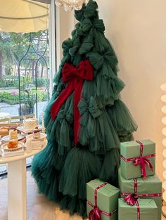 a christmas tree made out of green tulle and red bow sitting next to presents