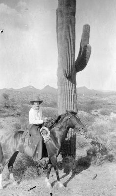 a man riding on the back of a horse next to a cactus