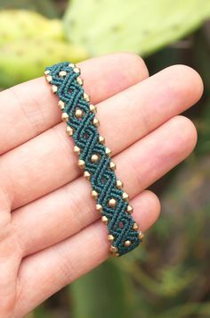 a hand holding a green beaded bracelet