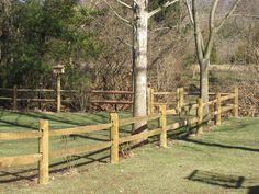 a wooden fence in the grass next to a tree