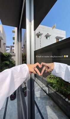 two people reaching out to touch each other's hand in front of a window