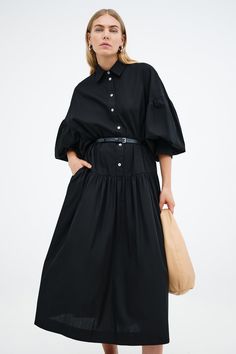 Meet our Ada Dress, the ultimate warm weather staple. She's a midi shirtdress handcrafted from 100% European poplin cotton, featuring pockets and a dropped gathered waistline that falls over your frame with ease. Her clean lines and sharp collar harmonize with dramatic dropped shoulders and full-bodied sleeves, elevating your style for any occasion.[SPLIT] Maritza, in black and in light blue, is 5'9.5" (177 cm) tall, wearing size XS. Shannon, in white, is 5'8" (173 cm) tall, wearing a size M. Mi Fall Midi Dress With Gathered Waist For Daywear, Cotton Dress With Voluminous Skirt For Daywear, Oversized Cotton Knee-length Midi Dress, Relaxed Fit Cotton Midi Dress With Collar, Spring Cotton Midi Dress With Pleated Sleeves, Spring Cotton Midi Dress With Pleated Waist, Cotton Midi Dress With Pleated Waist For Spring, Cotton Maxi Dress With Gathered Waist For Daywear, Cotton Pleated Midi Shirt Dress