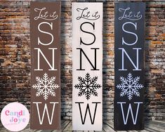 three wooden signs with snow designs on them next to a brick wall and the words let it snow