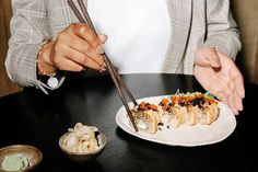 a woman holding chopsticks over a plate of sushi