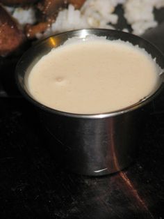 a metal bowl filled with white rice on top of a wooden table next to meat