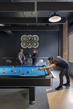 two men playing pool in an office setting