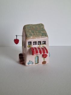 a small toy house with a strawberry hanging from it's roof