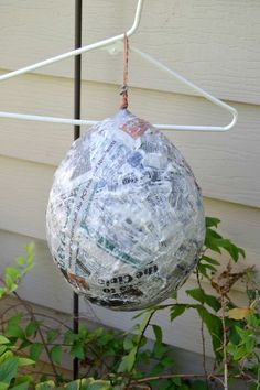 a plastic ball hanging from a clothes line in front of a house with green plants