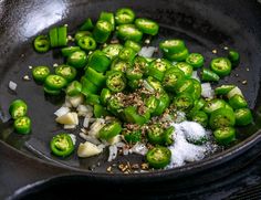 green peppers are being cooked in a skillet with garlic and seasoning on the side